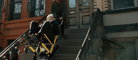 An older person seated in a Mobile Stairlift being taken down outdoor city steps