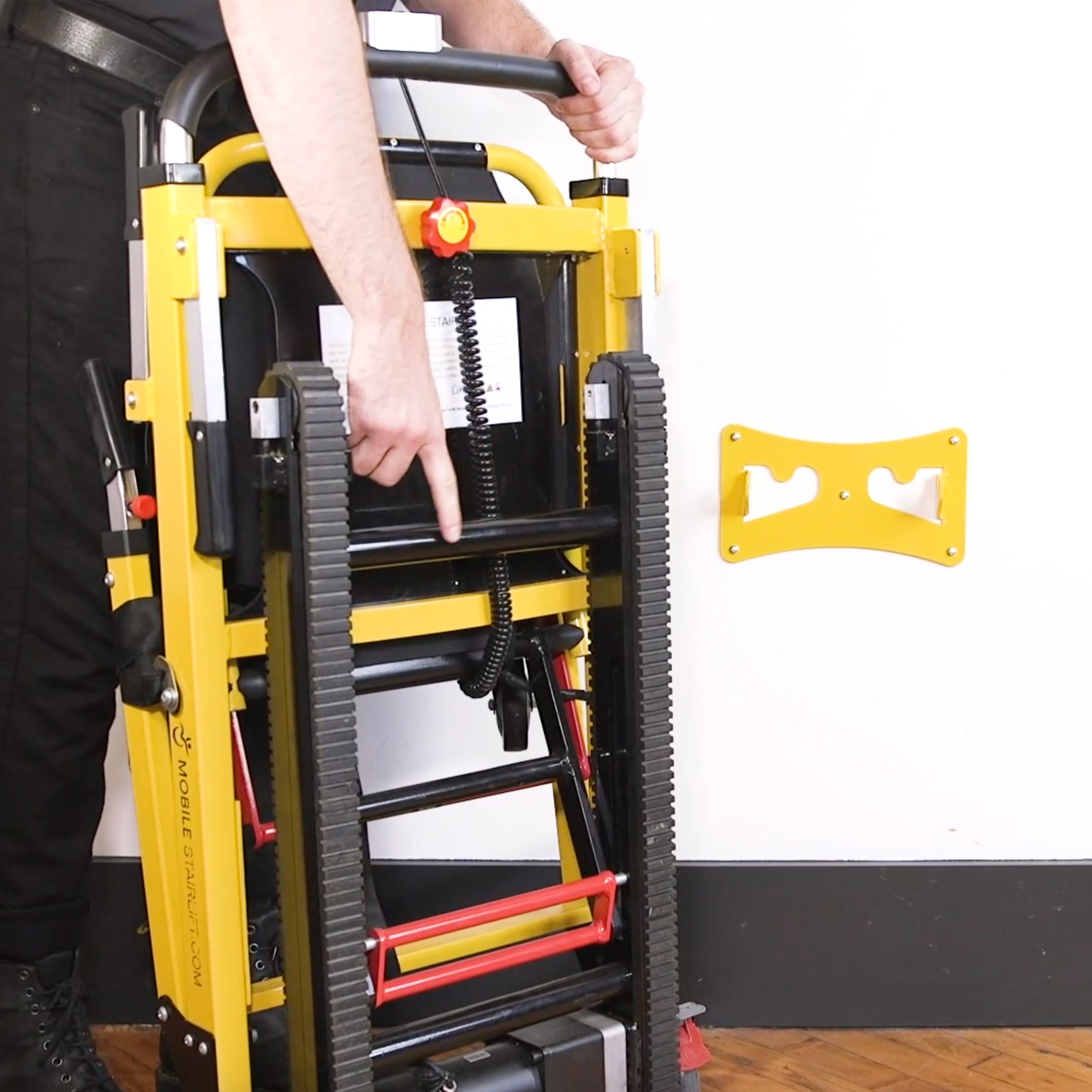 User positioning the Mobile Stairlift next to the wall mounted Storage Hook bracket for easy off-floor storage